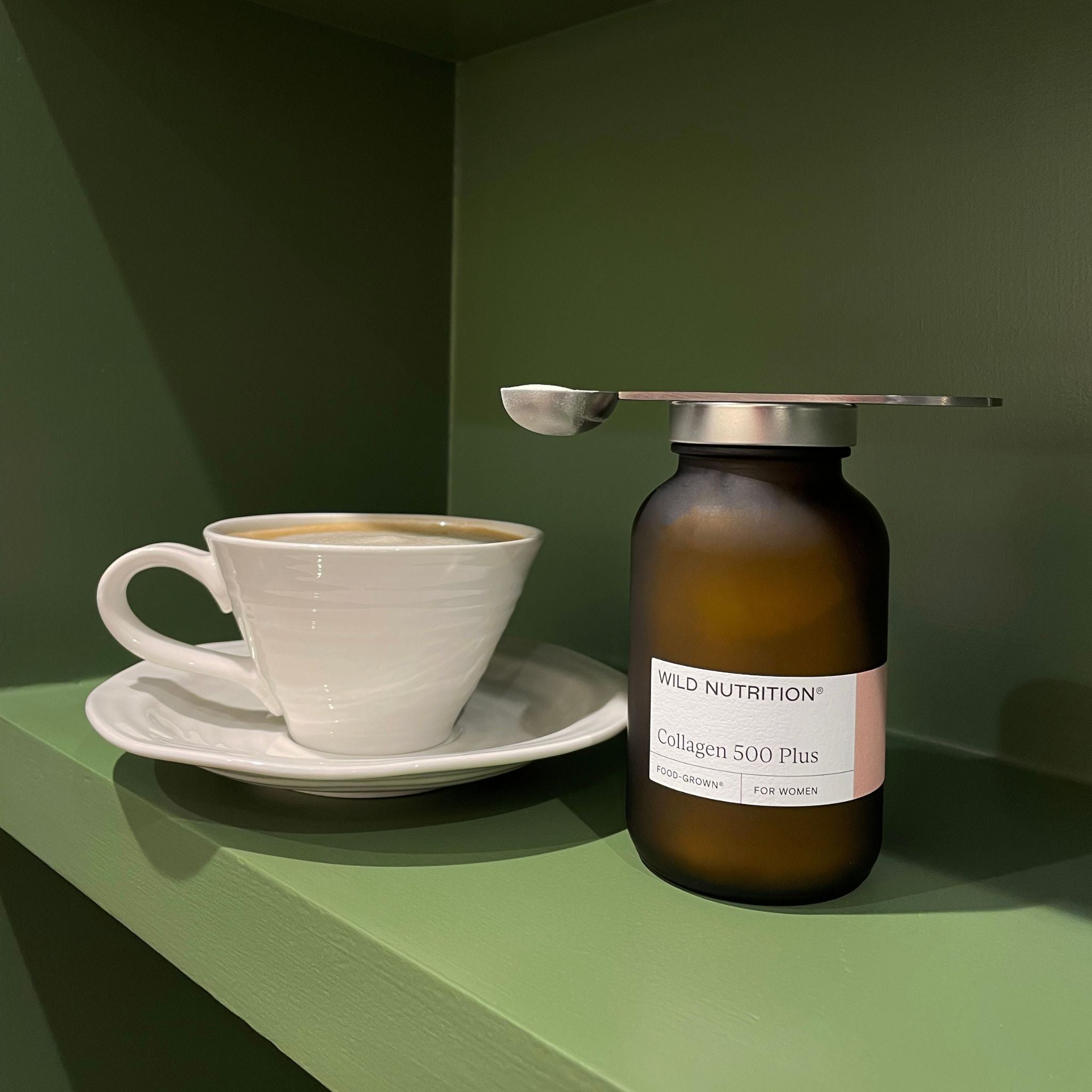  Wild Nutrition Collagen 500 Plus jar with metal scoop and coffee cup on green shelf