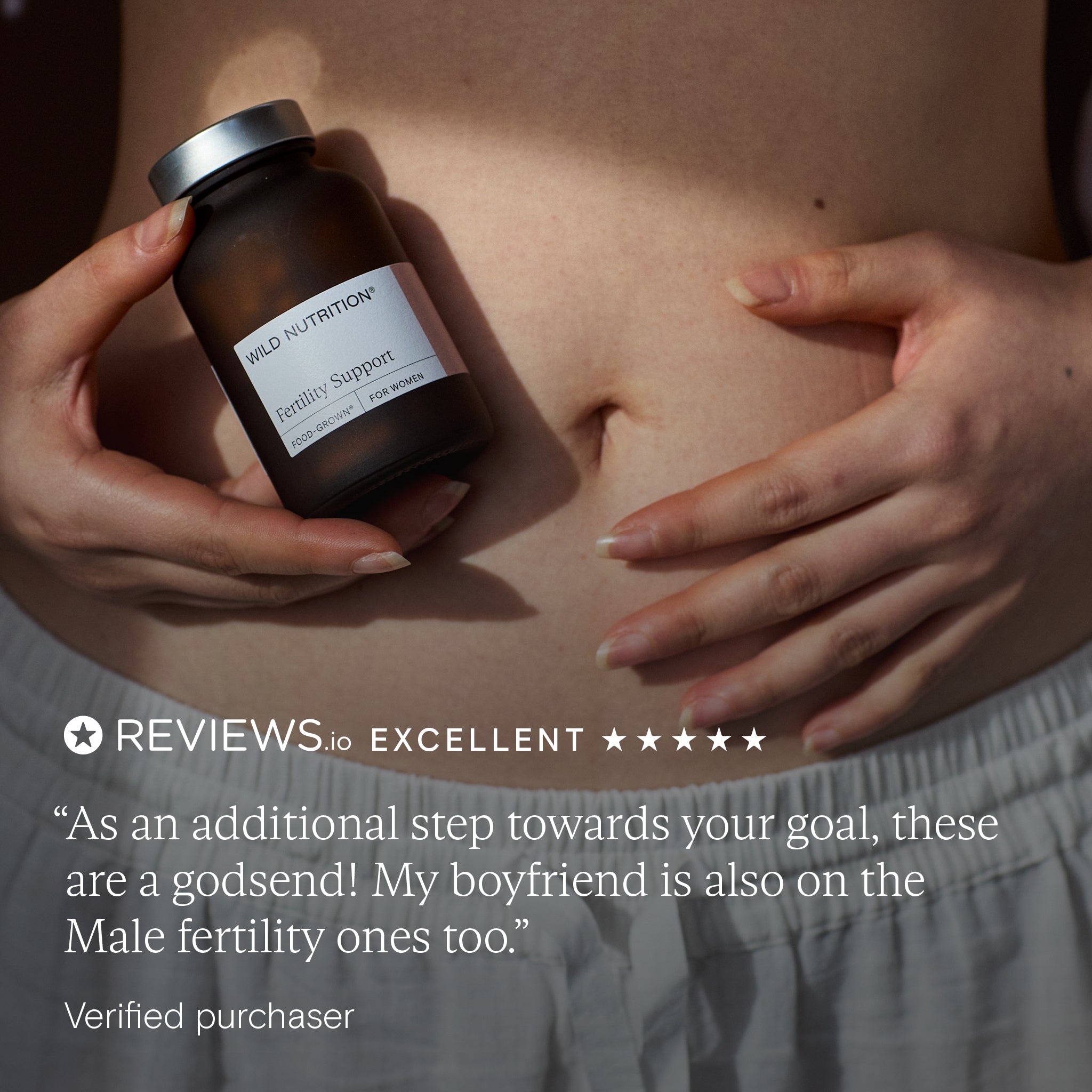 Wild Nutrition Fertility Support for women held near stomach with five-star Reviews.io rating and testimonial about fertility journey for couples