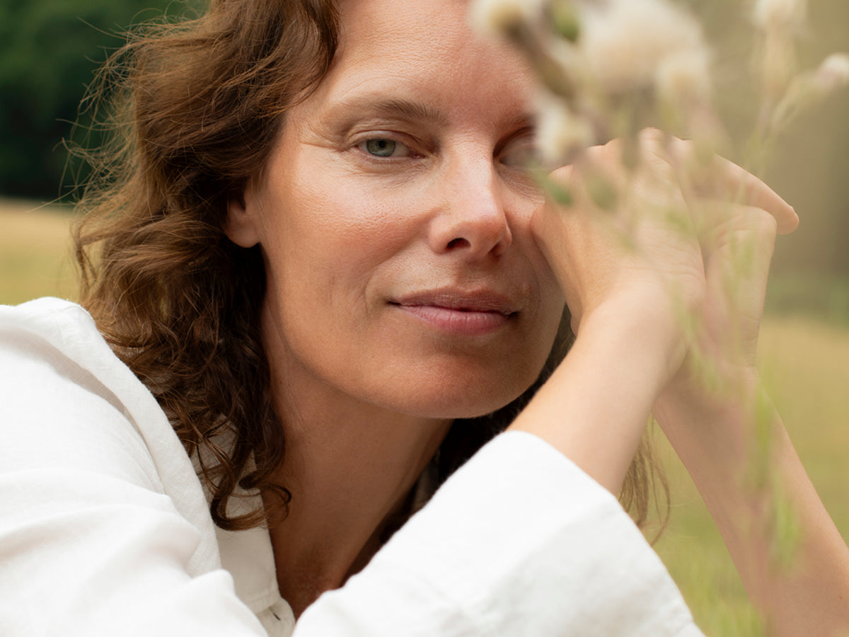 Relaxed woman outdoors in nature symbolizing balance and wellbeing supported by Wild Nutrition supplements.