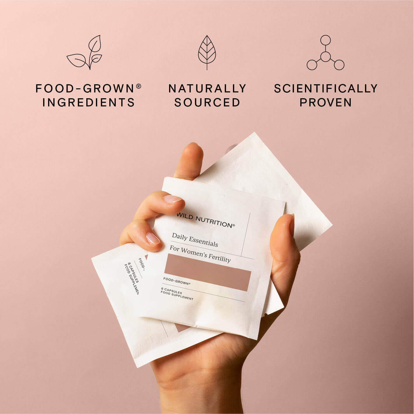Hand holding Daily Essentials sachets for women's fertility with icons for natural ingredients and scientific proof.