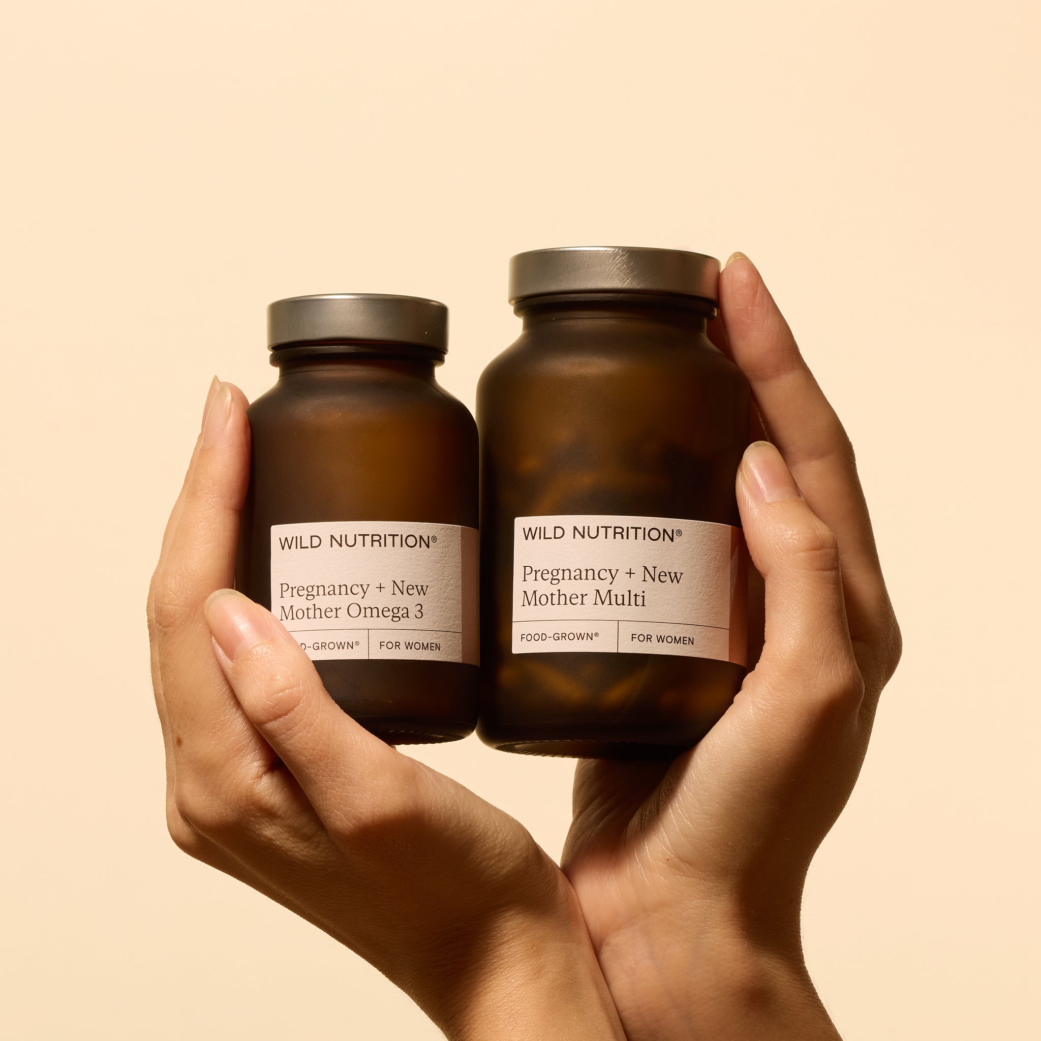 Hands holding Wild Nutrition's Pregnancy + New Mother Omega 3 and Multi vitamins for maternal and fetal health.