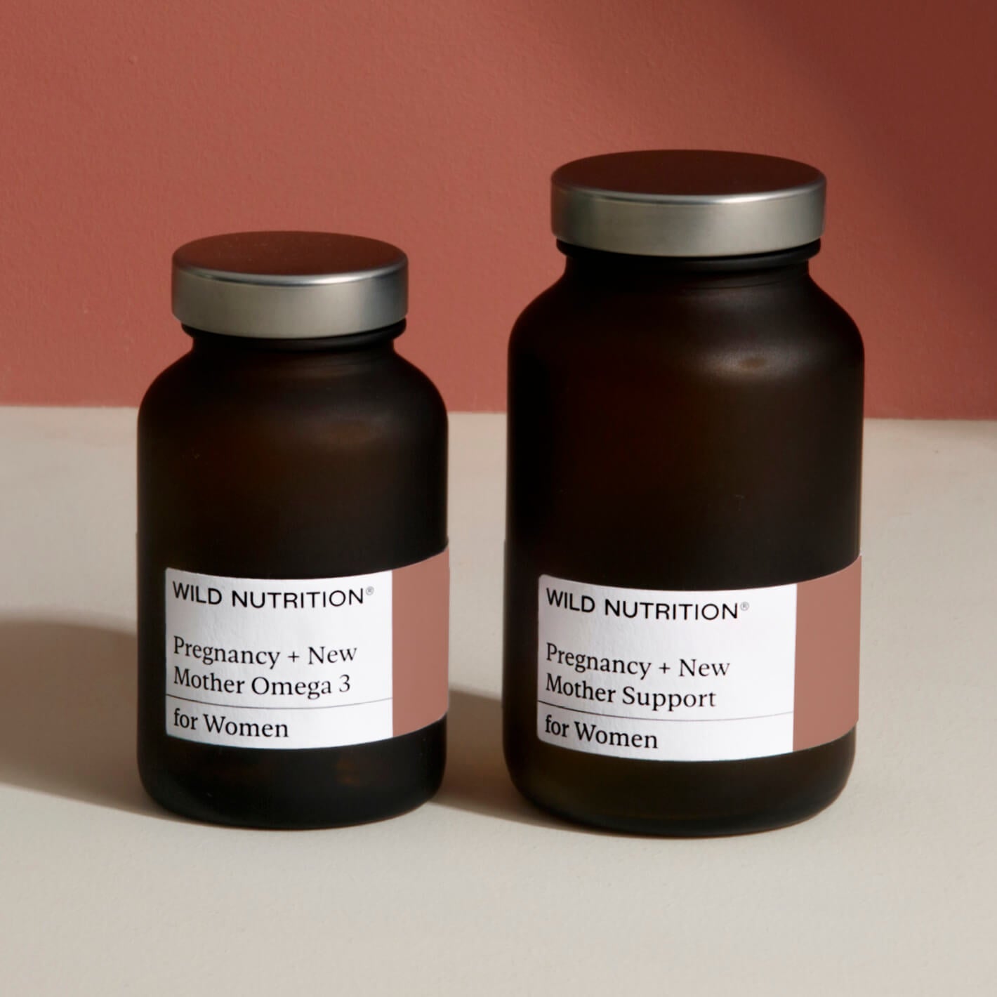 Two brown bottles labeled 'Pregnancy + New Mother Omega 3' and 'Pregnancy + New Mother Support' for women's health.