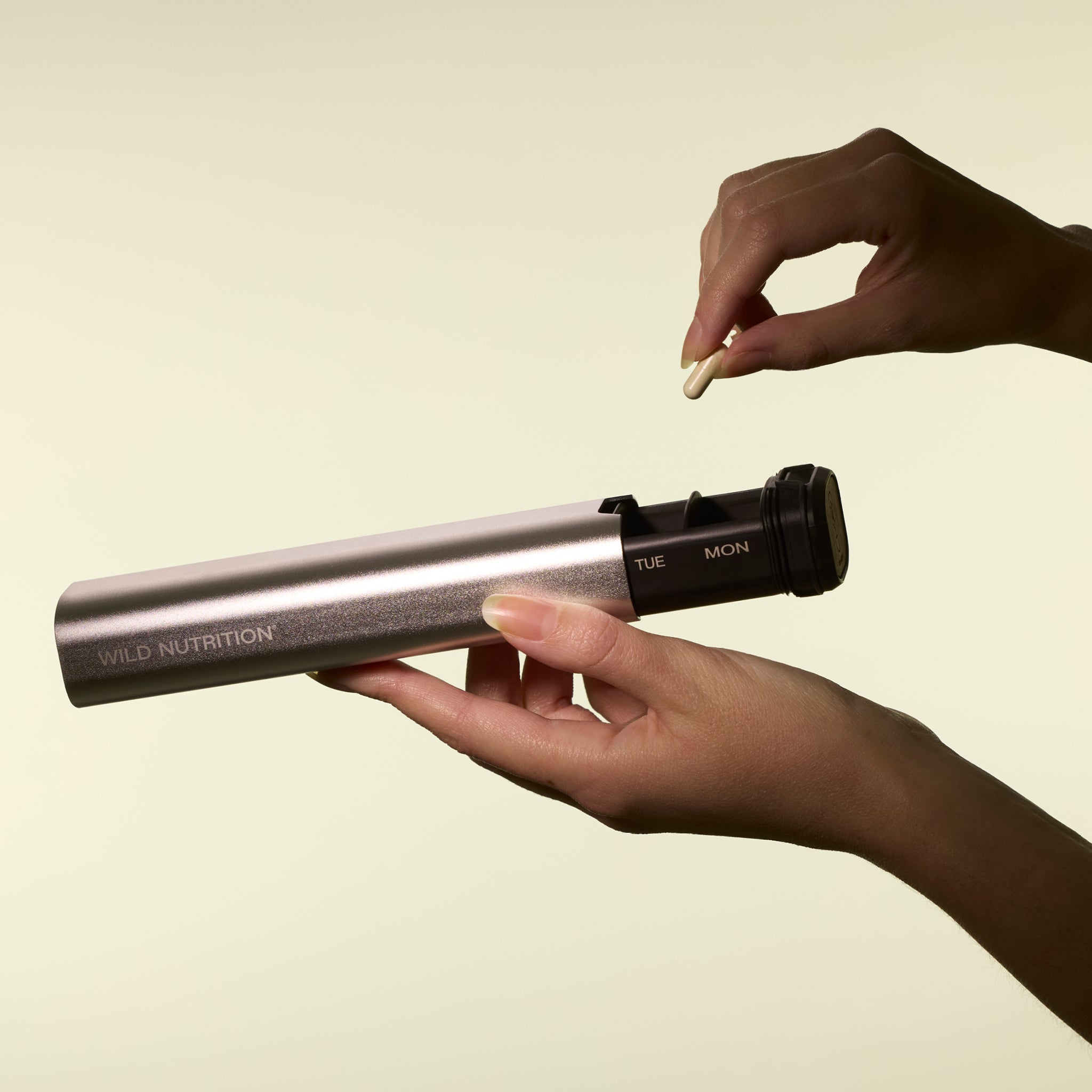 Hands demonstrating how to remove supplements from Wild Traveller organiser, highlighting user-friendly design for daily dosage management