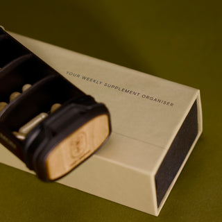 Close-up of open Wild Traveller supplement organiser showing inner pill compartments and eco-friendly wooden cap