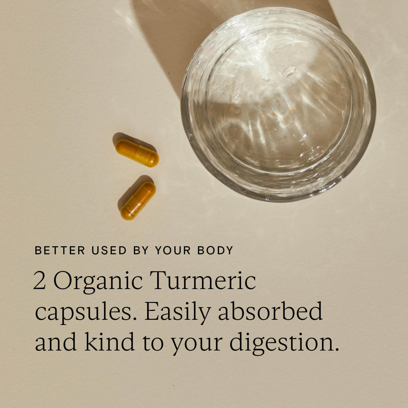 Two organic turmeric capsules next to glass of water showing easy digestion and absorption