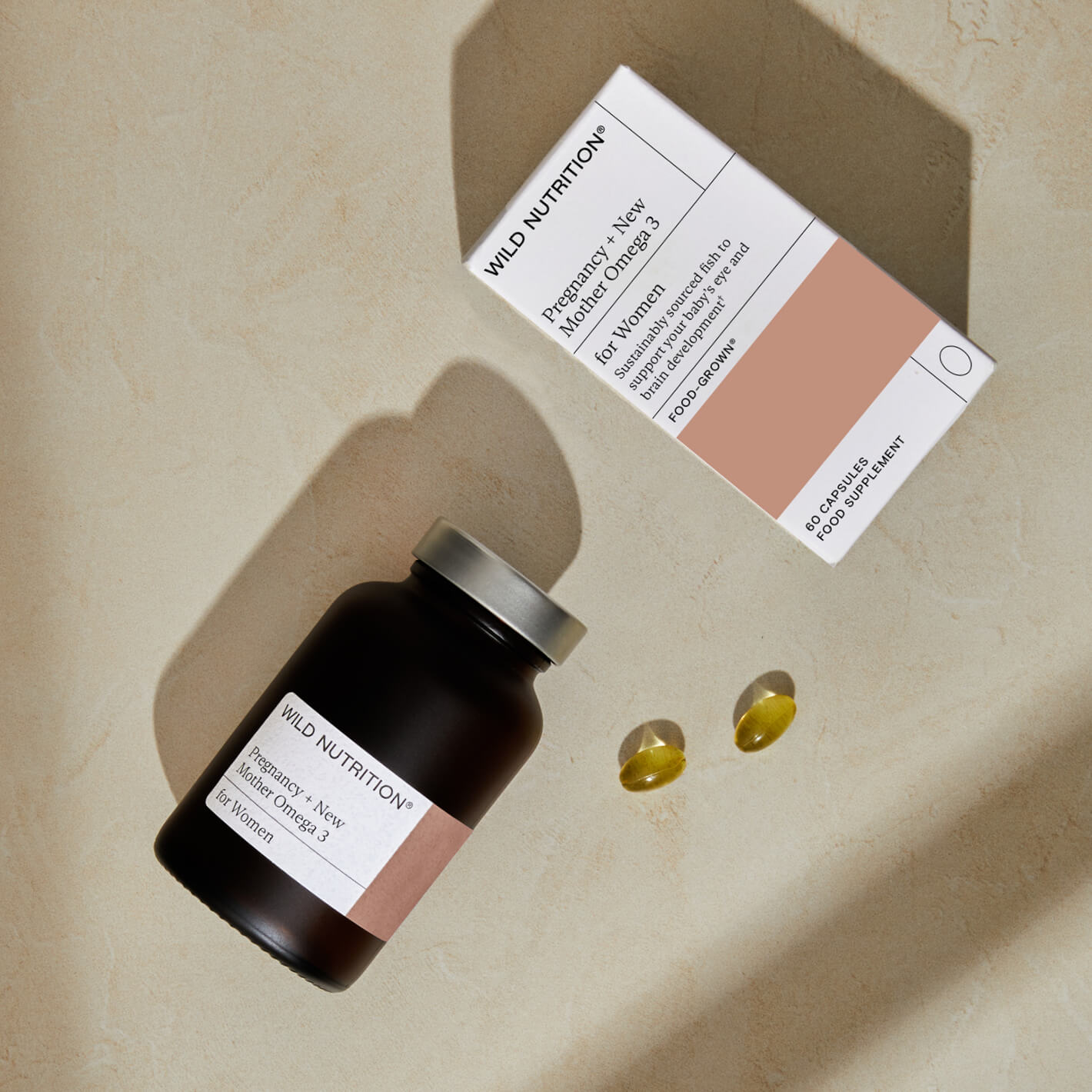 Food-Grown® Pregnancy + New Mother Omega 3 supplements in a jar with softgel capsules and box on a beige background.